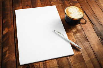 Blank branding template on vintage wooden table background. Photo of blank letterhead, coffee cup and pen. Blank stationery set. Blank mock-up for your design.