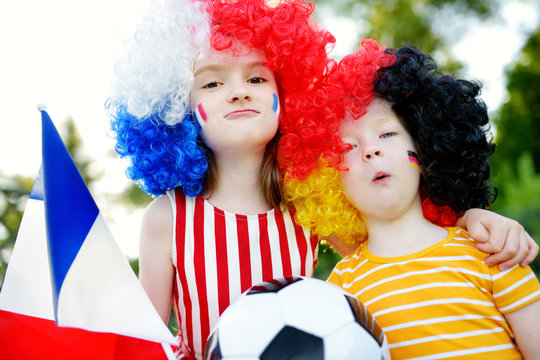 Two funny little sisters supporting and cheering their national football teams