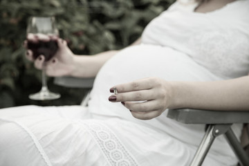 Obraz na płótnie Canvas Young pregnant woman holding wine and cigarette