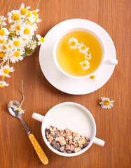 Muesli mix with yogurt in a bowl and chamomile tea