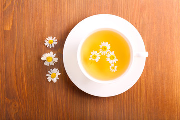 Chamomile tea in a cup on wooden surface