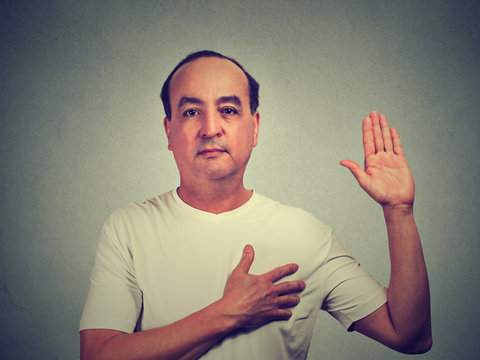 Middle aged man making a promise isolated on gray wall background