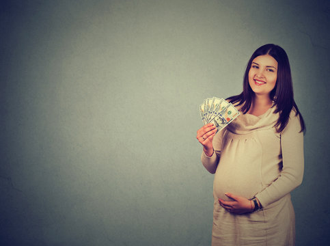 Happy pregnant woman with cash dollar banknotes bills