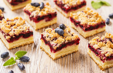 Honeysuckle Crumb Cake  sliced into pieces on a light background with berries of honeysuckle and flowers 