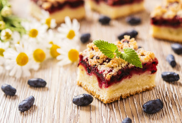 Honeysuckle Crumb Cake  sliced into pieces on a light background with berries of honeysuckle and...