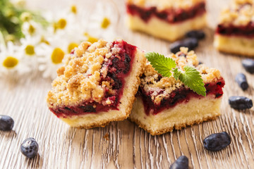 Honeysuckle Crumb Cake  sliced into pieces on a light background with berries of honeysuckle and flowers 