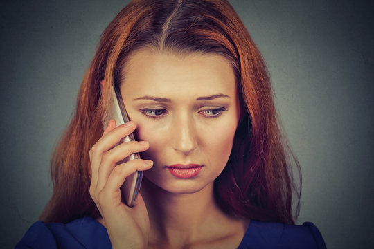 unhappy young woman talking on mobile phone looking down