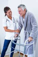 Female doctor helping senior man to walk with walker