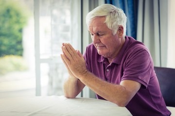 Senior man praying in living room