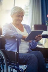 Happy senior woman on wheelchair using digital tablet