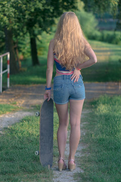 Young skateboarder girl posing outdoor with skateboard
