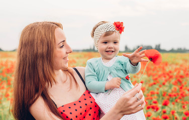 mother and daughter walking and having fun in poppy field