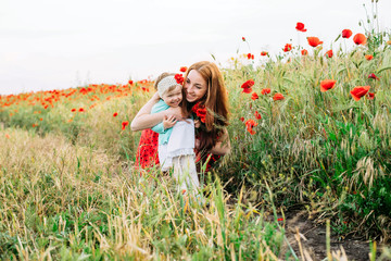 mother and daughter walking and having fun in poppy field