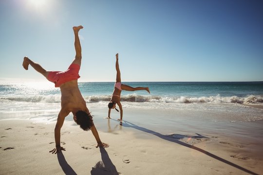 Couple Performing Somersault On Beach