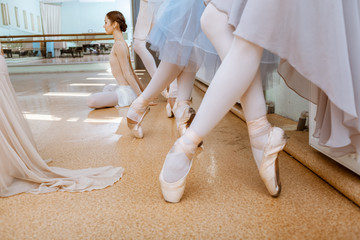 Fototapeta premium The close-up feet of young ballerinas in pointe shoes