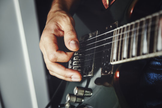 man playing electric guitar close up view, very shallow depth of field image, cinematic effect applied