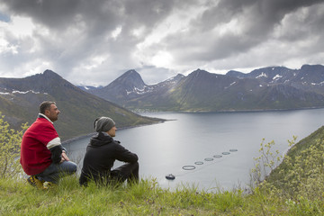 zwei Männer genießen Aussicht über Fjord auf Senja, Norwegen