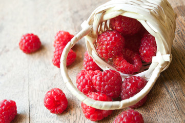 framboises et petit panier en osier sur table en vieux bois