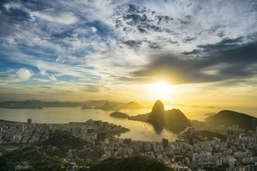 Scenic sunrise in Rio de Janeiro Brazil glows golden over Guanabara Bay with a skyline silhouette...