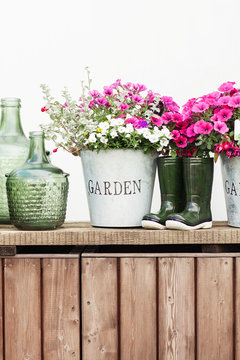 Flowers in a bucket, glass vintage bottles on wooden background,