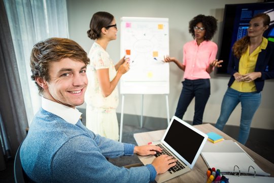 A colleague using laptop smiling at camera