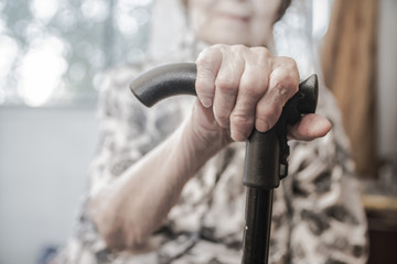 wrinkled hands of an old woman pensioner grandmothers on the cane stick