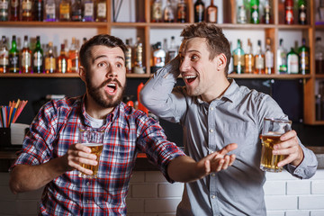 Young people with beer watching football in a bar