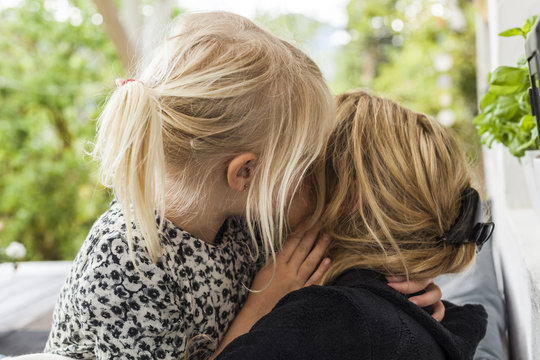 Blond little girl kissing her mother