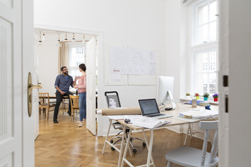 Two creative professionals talking in office