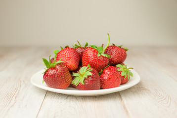 Ripe red strawberry on a white plate