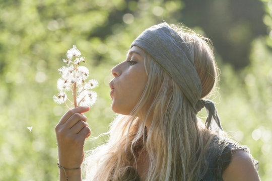 Blond woman blowing seeds of an umbel into the air
