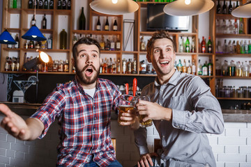 Young people with beer watching football in a bar