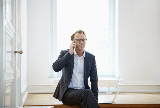 Smiling businessman telephoning with smartphone
