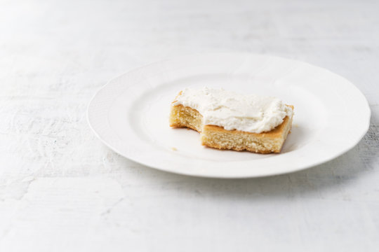 Lemon cake with curd cream on white plate, bitten