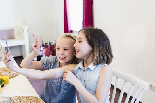 Two girls taking a selfie at table