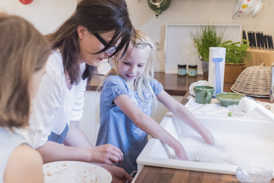 Mother and two girls washing the dishes in kitchen