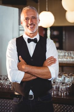 Portrait of bartender standing with arms crossed