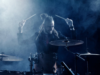 Silhouette drummer on stage. Dark background, smoke spotlights
