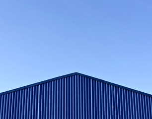 Fototapeta na wymiar Blue modern warehouse roof against blue sky.