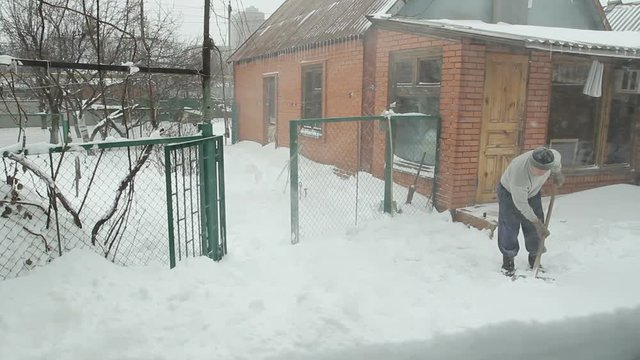 Man with snow shovel cleans street