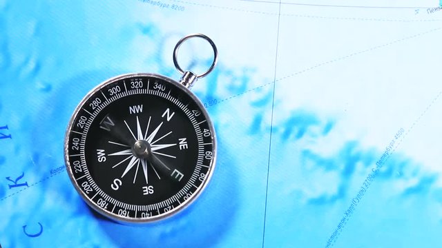 compass on a wooden table and a map in the background