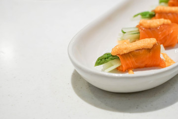 Part of salmon roll with cucumber and asparagus on the white plate