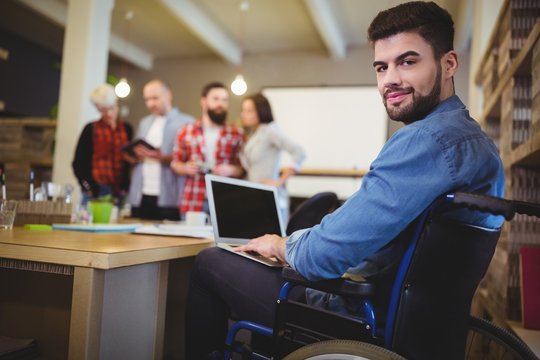 Smart disabled businessman using laptop at desk 