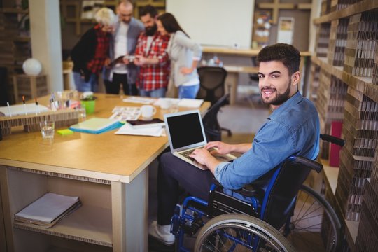 Confident disabled businessman using laptop at desk 