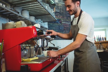 Happy barista using coffee maker at cafe
