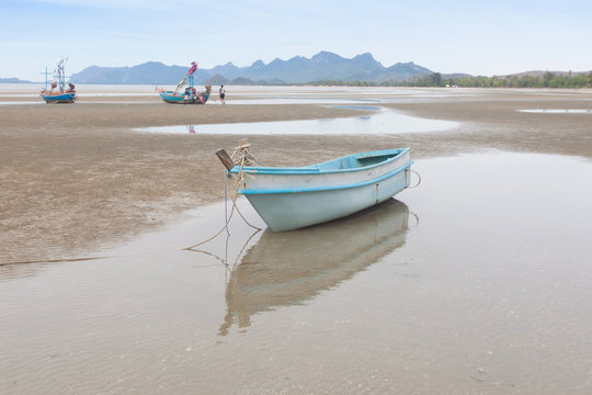 Reflection of fiberglass boat on  low tide beach .