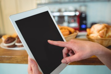 Close-up of barista finger scrolling tablet pc at cafe