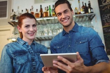 Portrait of cheerful baristas with digital tablet at cafe