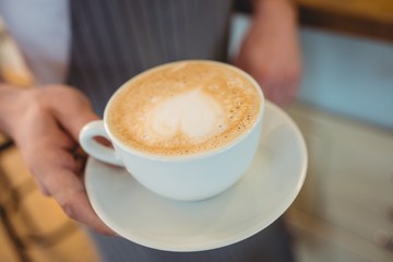 Close-up of coffee served by waitress at cafe