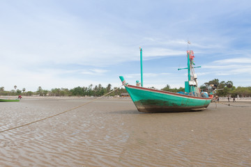 Naklejka na ściany i meble Green wooden fishing boat on the low tide beach.
